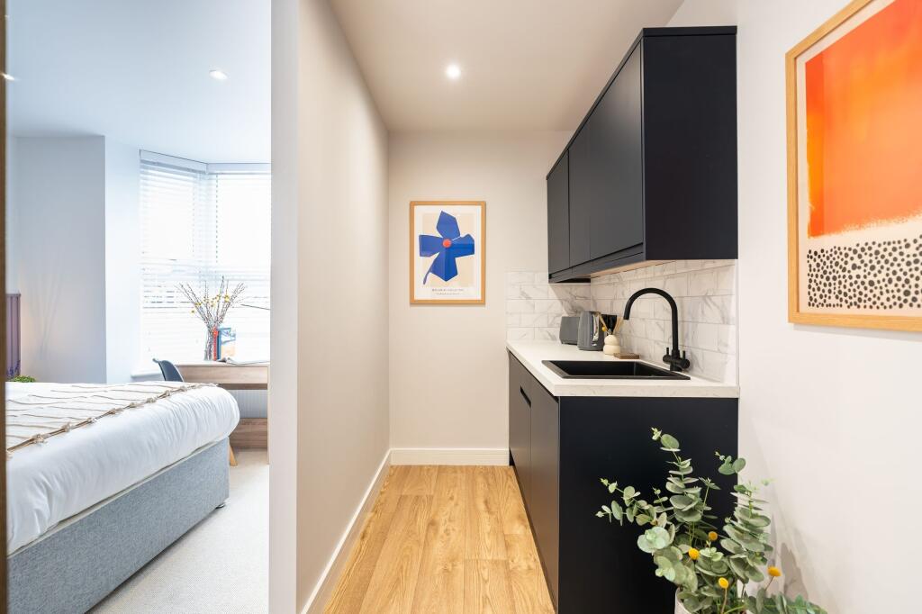 Modern and stylish compact kitchen featuring sl...