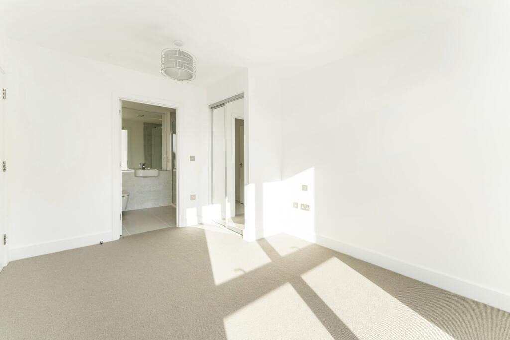 Bright and airy bedroom featuring clean, neutra...