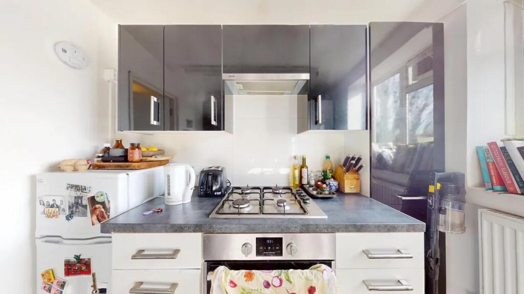 Modern kitchen featuring glossy black cabinets,...