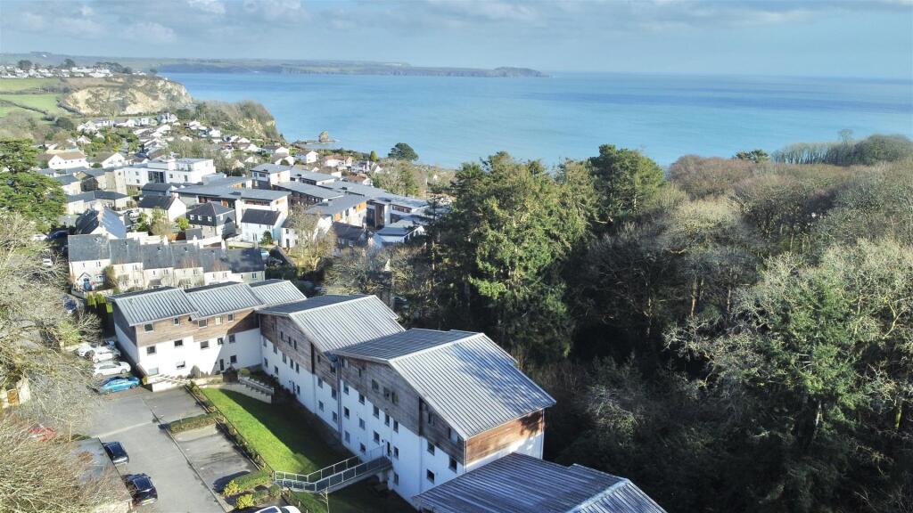 Aerial View of the development, nearby woodland and coast.