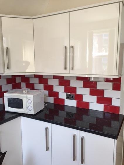 A modern kitchen area featuring sleek white cab...