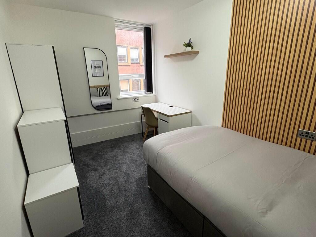 A modern, tidy single bedroom featuring a full-...