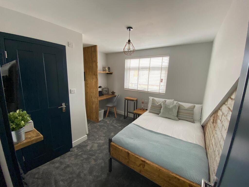 A modern, well-lit bedroom featuring a comforta...