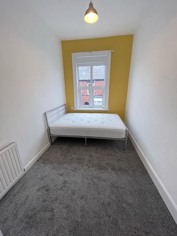 A cozy single bedroom featuring a clean, bright...