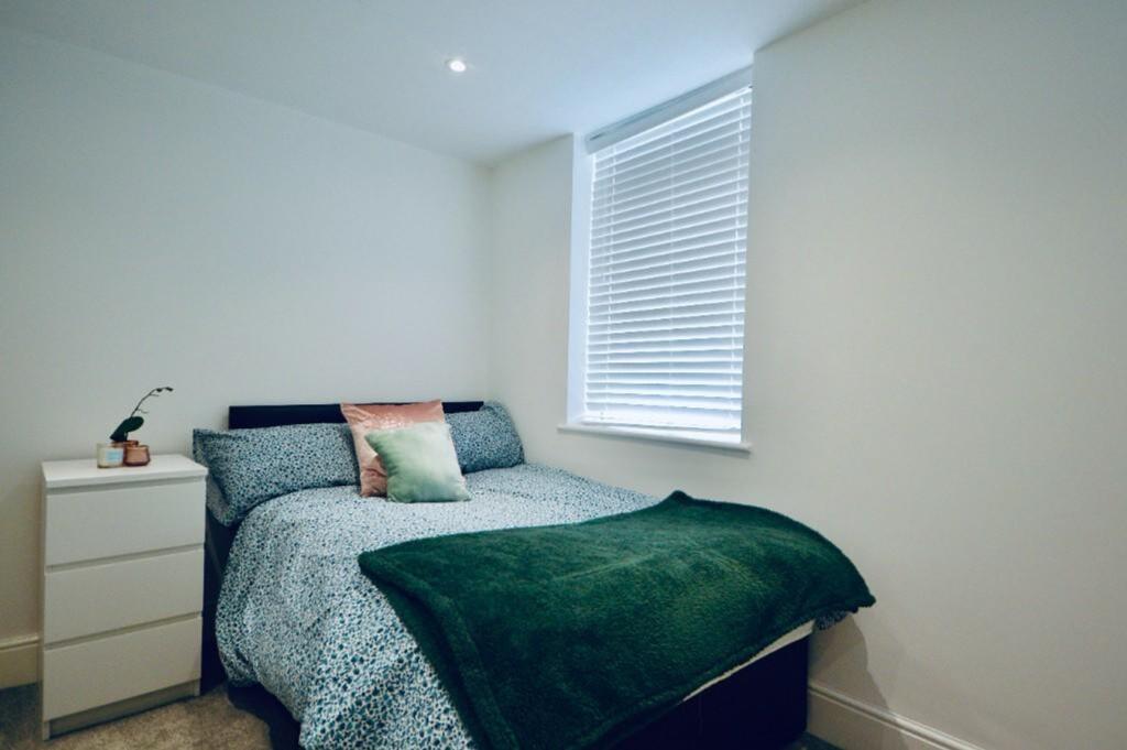 A bright and tidy double bedroom with a cozy at...