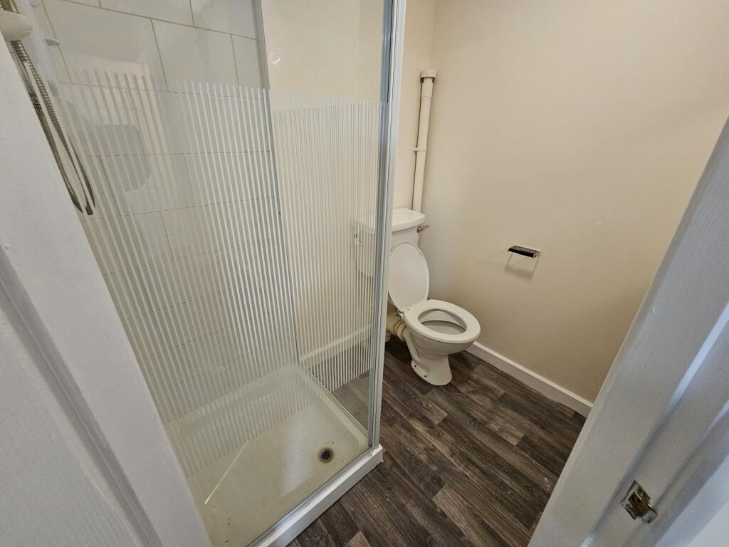 Compact bathroom with a corner shower enclosure...