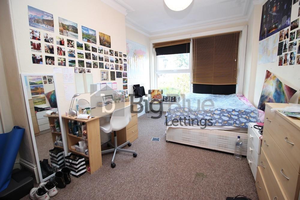A cozy single bedroom with a neatly made bed, a...