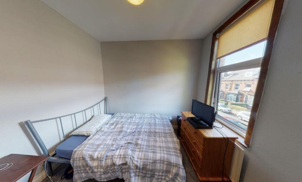 A well-lit single bedroom featuring a comfortab...