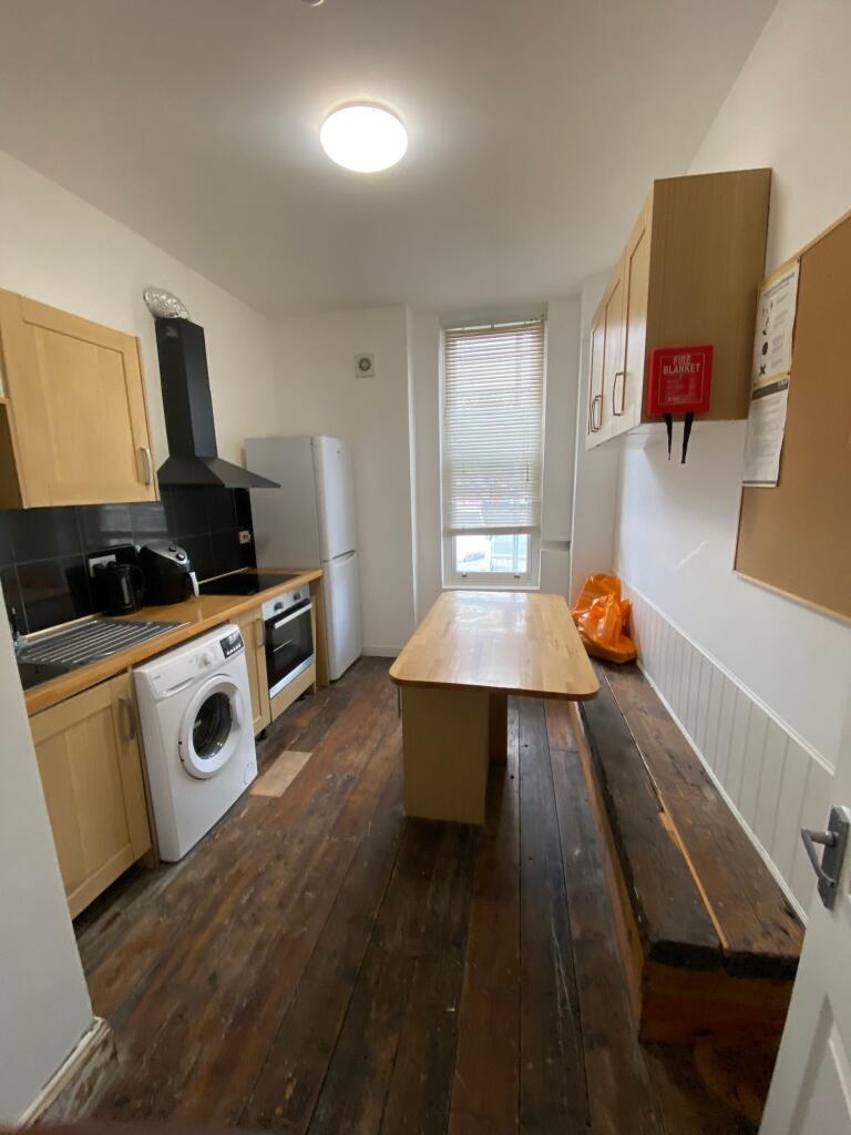A compact kitchen featuring wooden cabinetry, a...