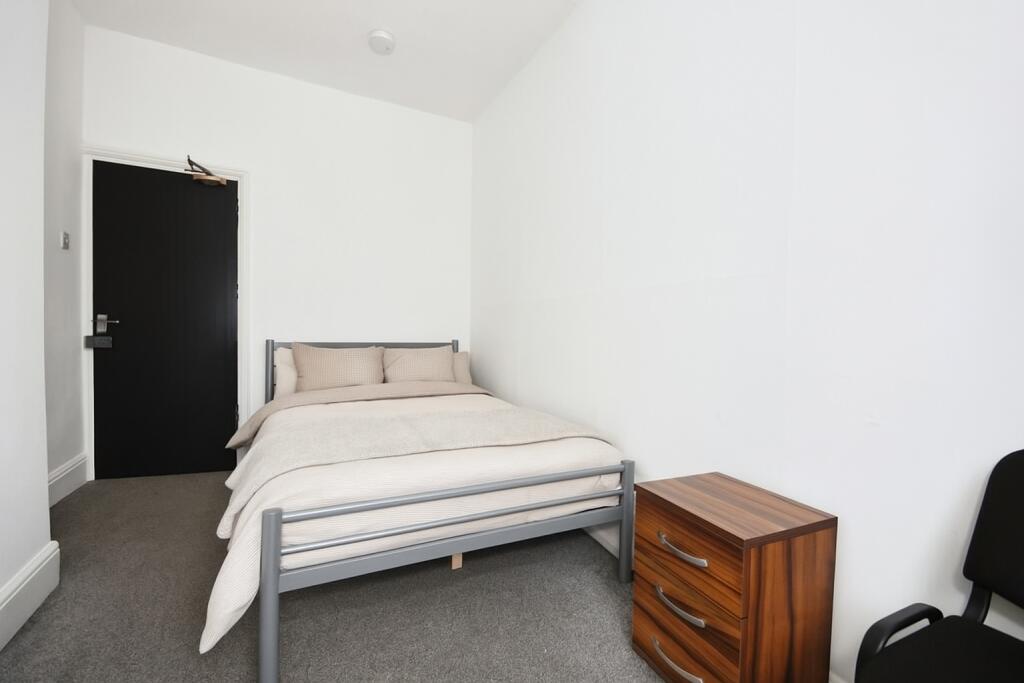 Bright, simply furnished bedroom with a metal d...