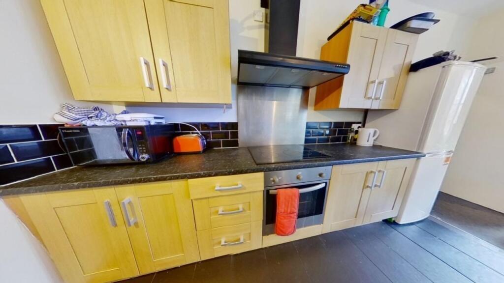 A modern kitchen featuring light wooden cabinet...