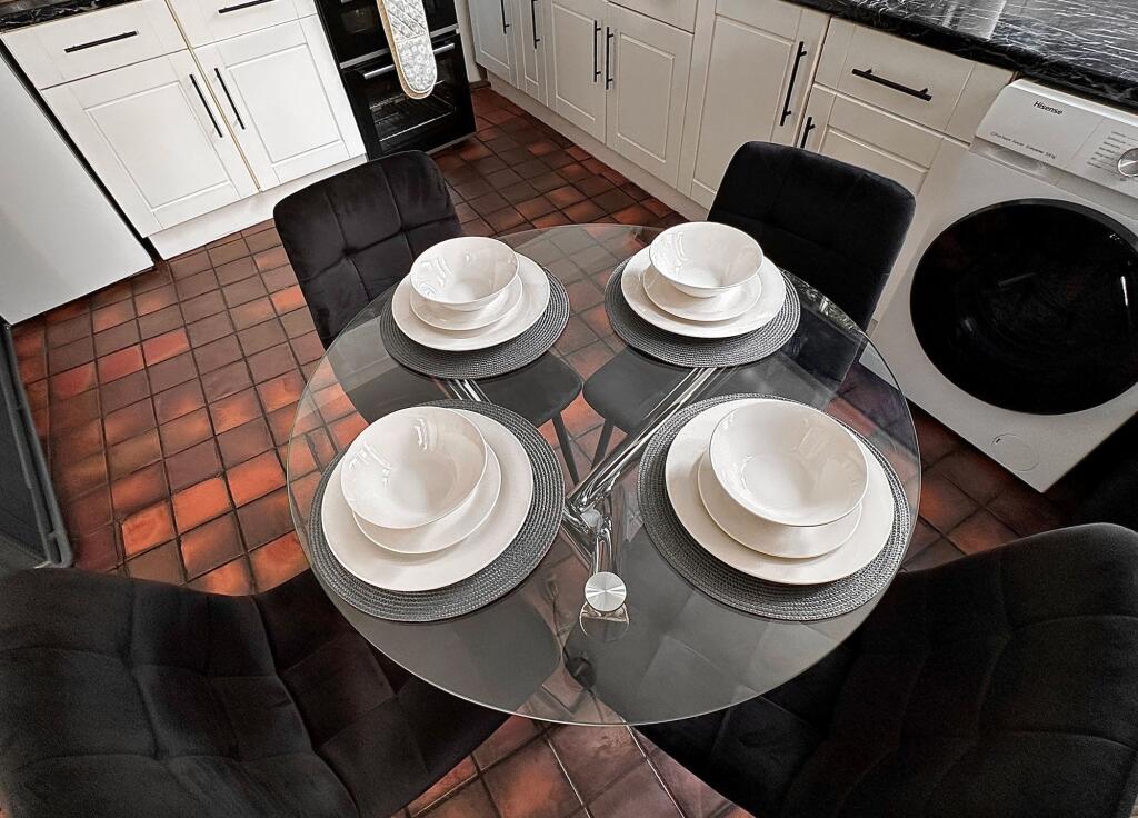 A modern kitchen featuring a sleek glass dining...