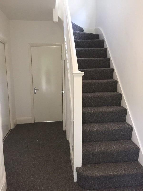 Bright and clean hallway featuring a carpeted s...