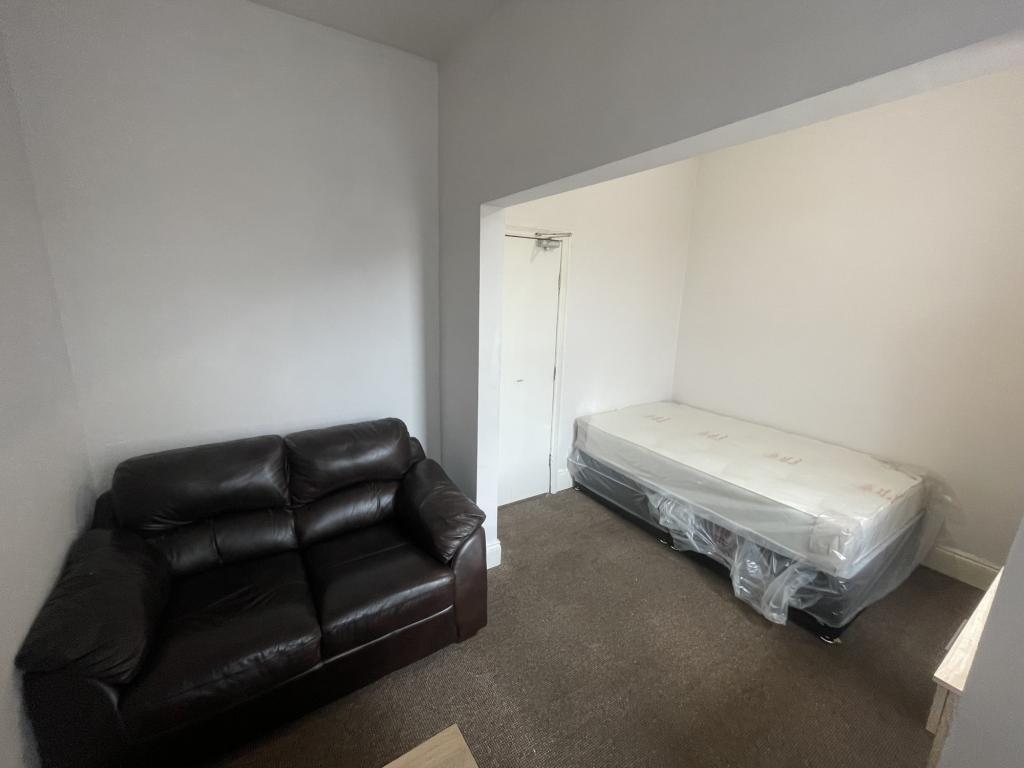 Compact bedroom with a comfortable dark leather...