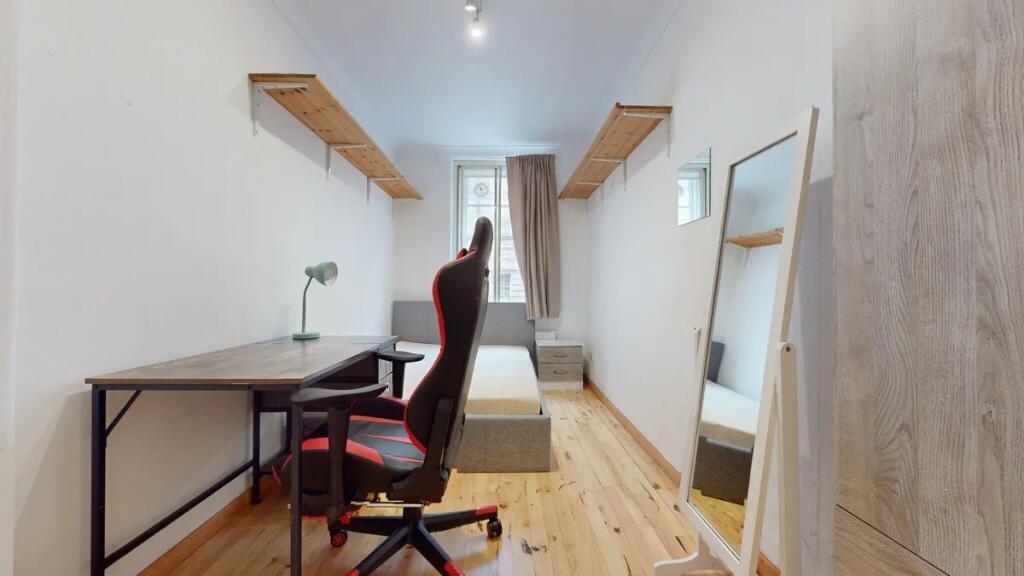 A neat and tidy single bedroom featuring a comf...