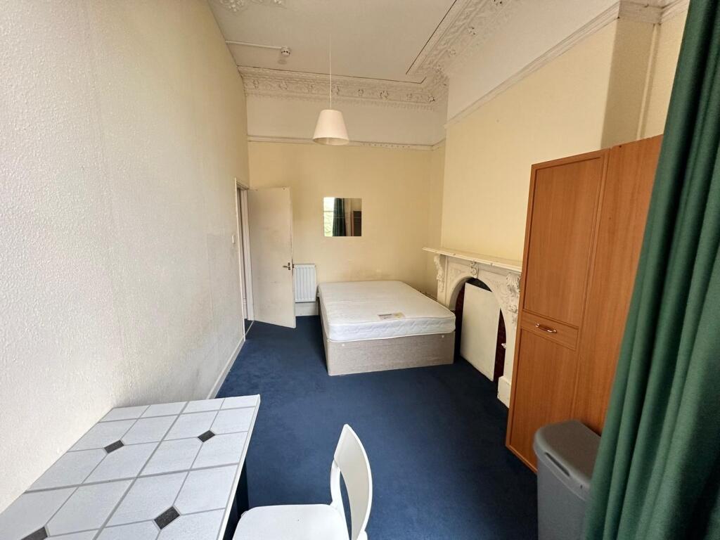 A spacious and inviting double bedroom with cha...