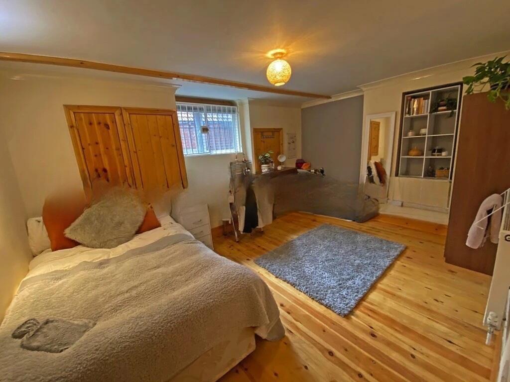 A cozy single bedroom featuring warm wood floor...