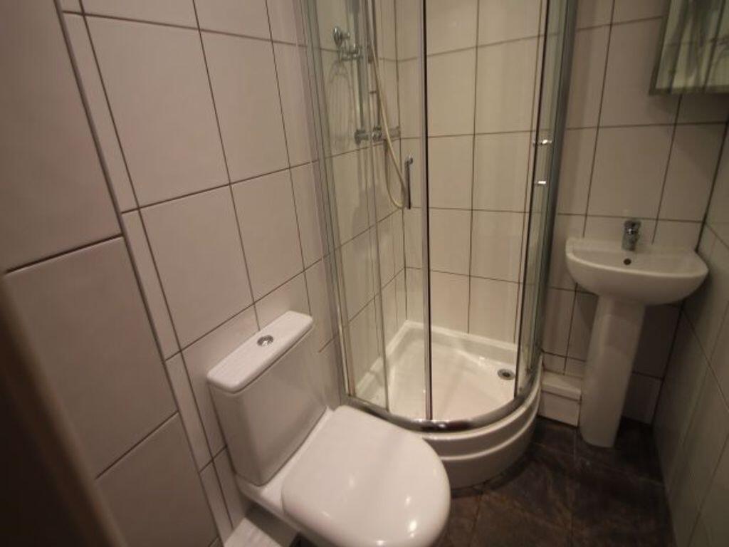 Modern tiled bathroom with a corner glass showe...