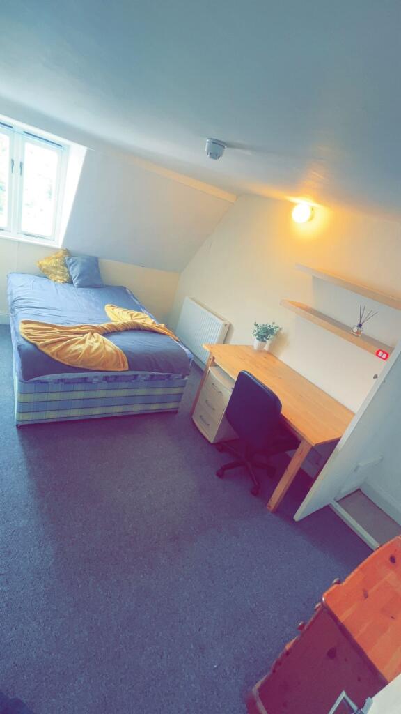 A cozy single bedroom with a large window provi...