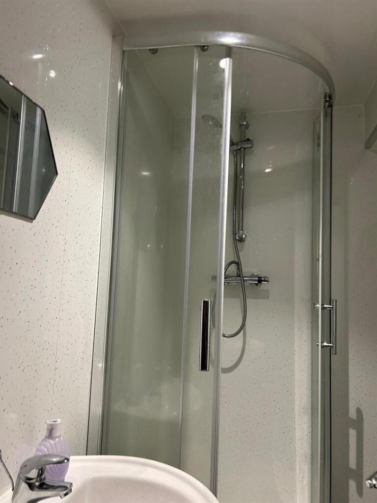 A modern bathroom featuring a curved glass show...