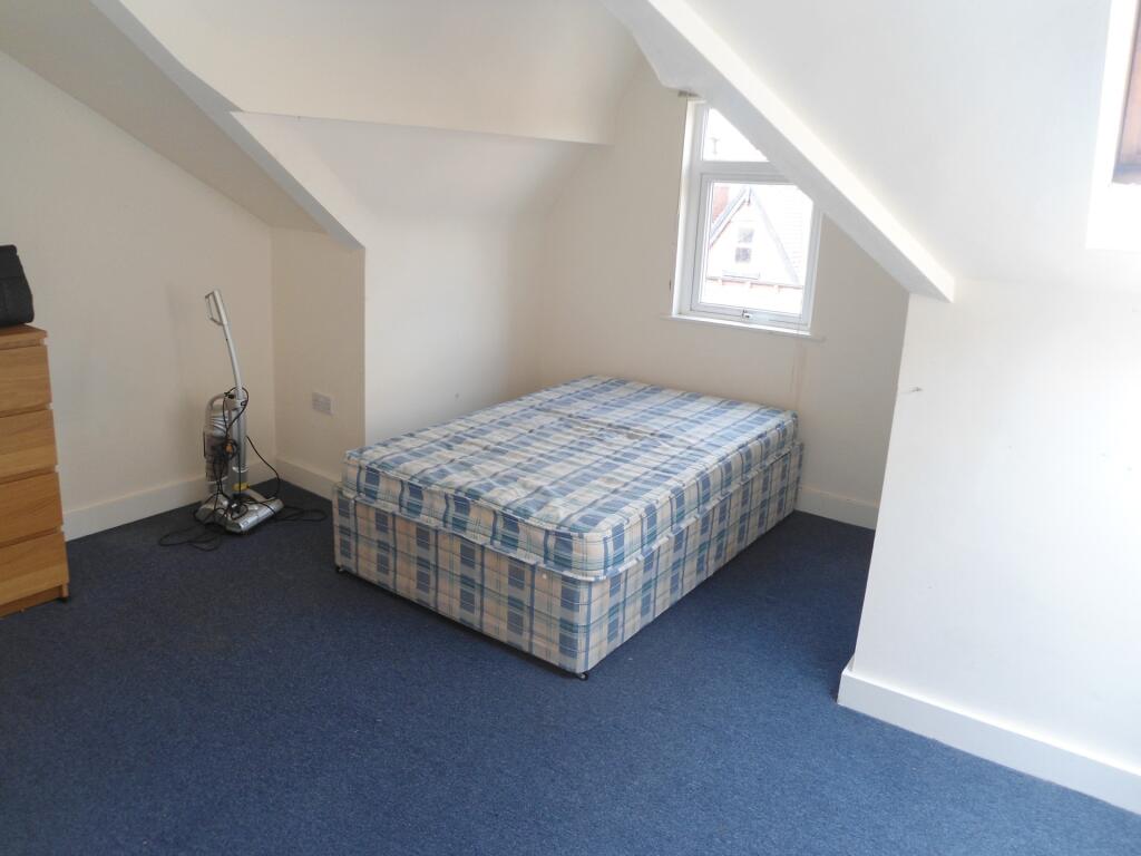 A tidy, well-lit small bedroom with a single ma...