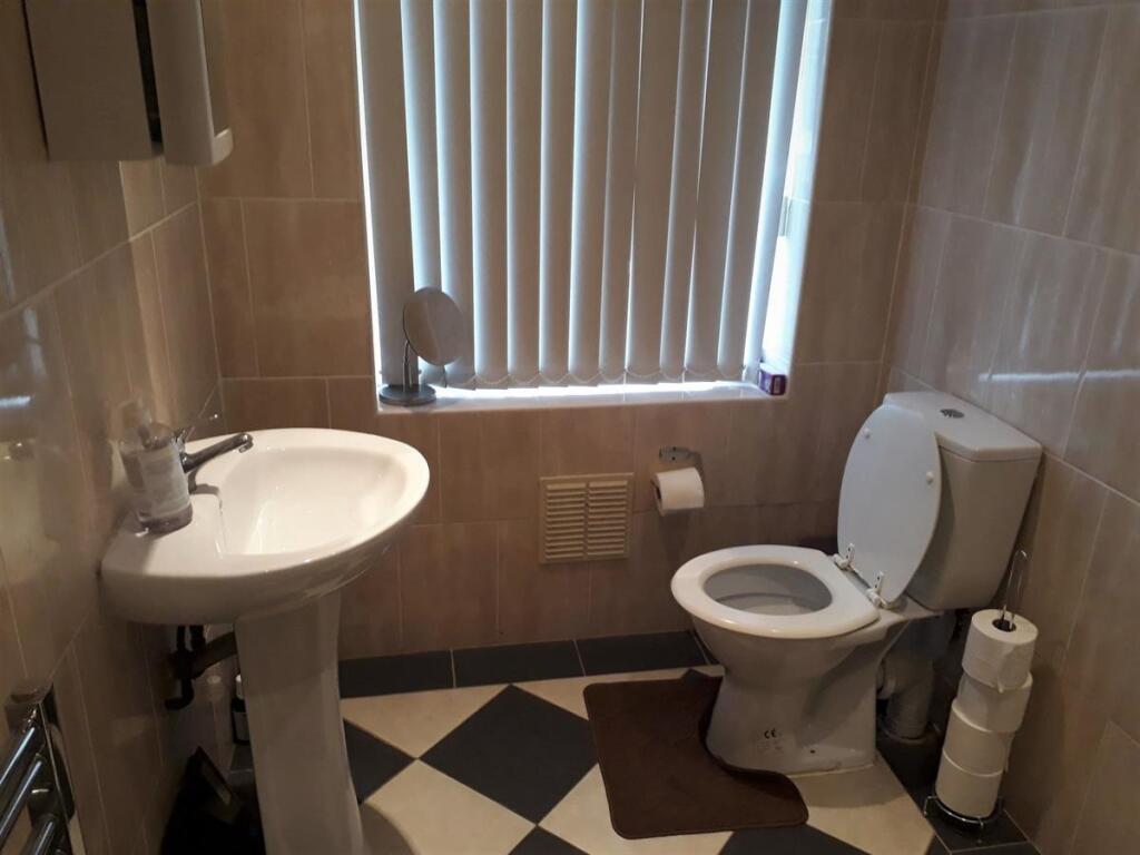 Bright tiled bathroom with a pedestal sink, toi...
