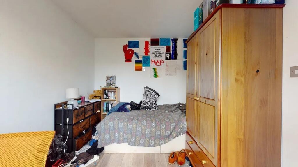 Cozy single bedroom featuring a wooden wardrobe...