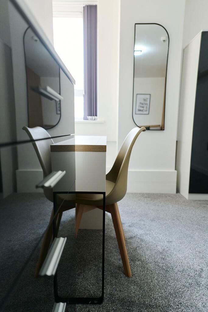 A modern, tidy single bedroom featuring a sleek...