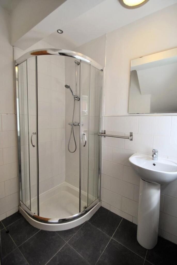 A modern bathroom featuring a curved glass show...