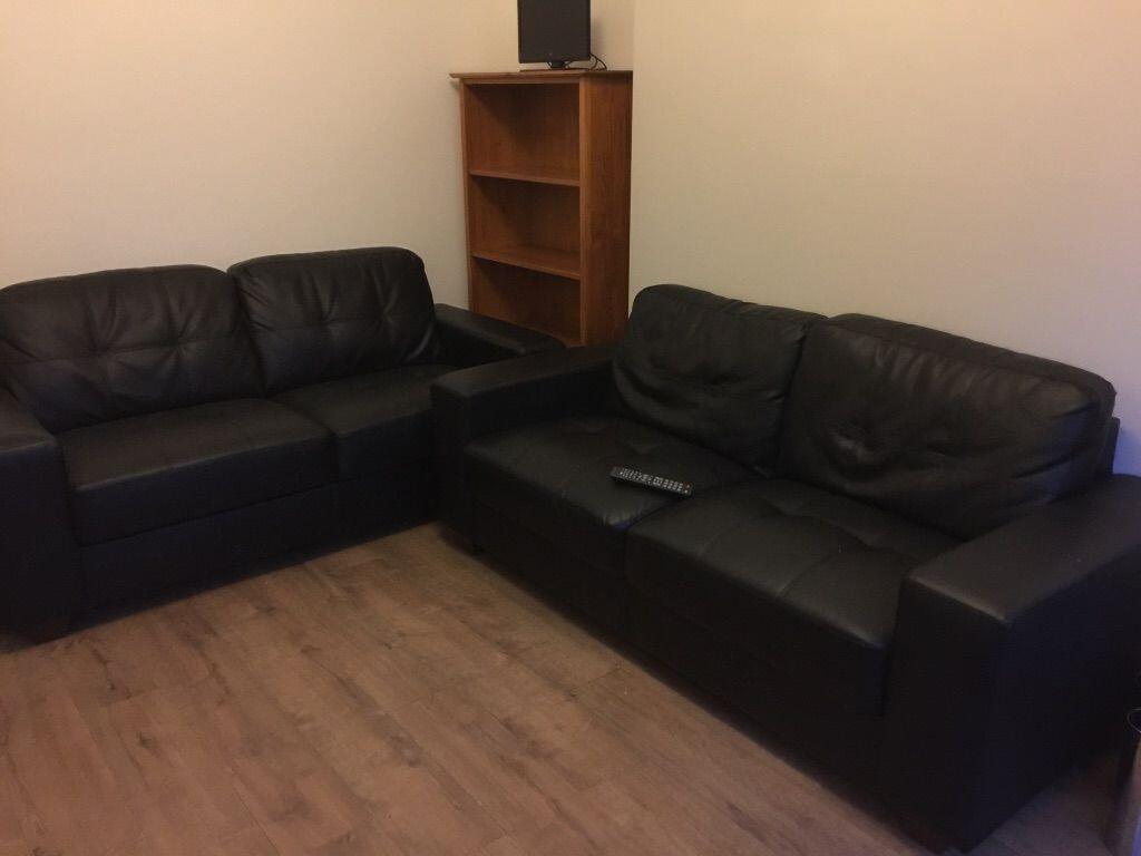 Neat living room with two black leather sofas a...