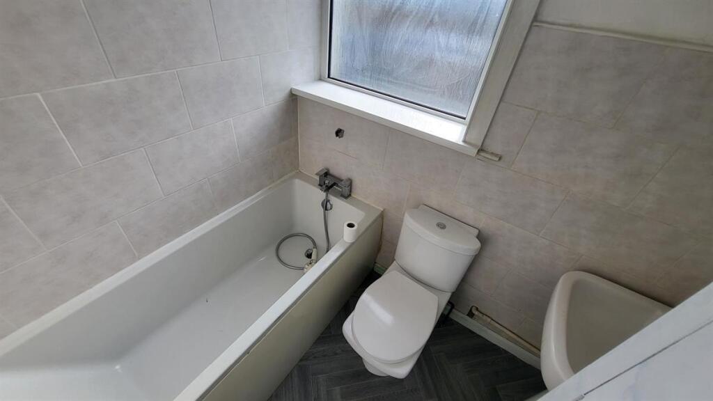 Clean, modern bathroom with a white bathtub, cl...