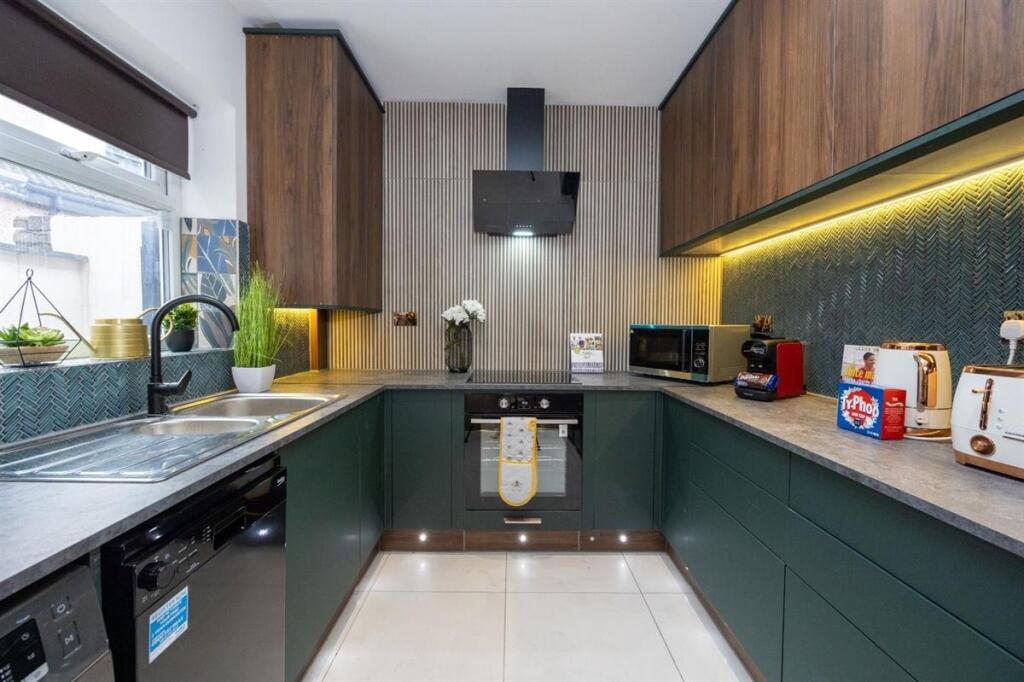 A modern kitchen featuring sleek dark green low...