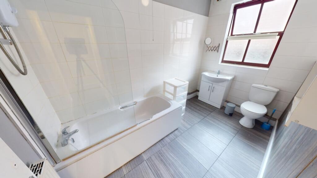 A spacious and bright bathroom featuring a bath...
