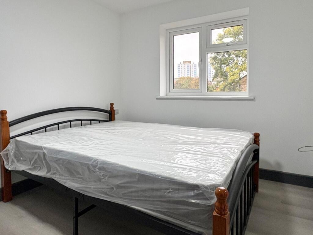 Bright, simply furnished bedroom with a metal d...