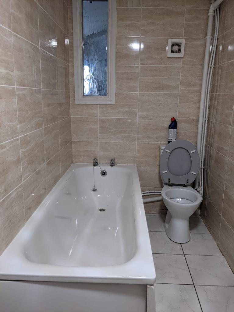 A clean bathroom featuring a bath and a toilet,...