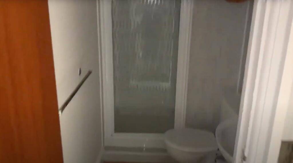 A compact bathroom with a shower enclosure, toi...