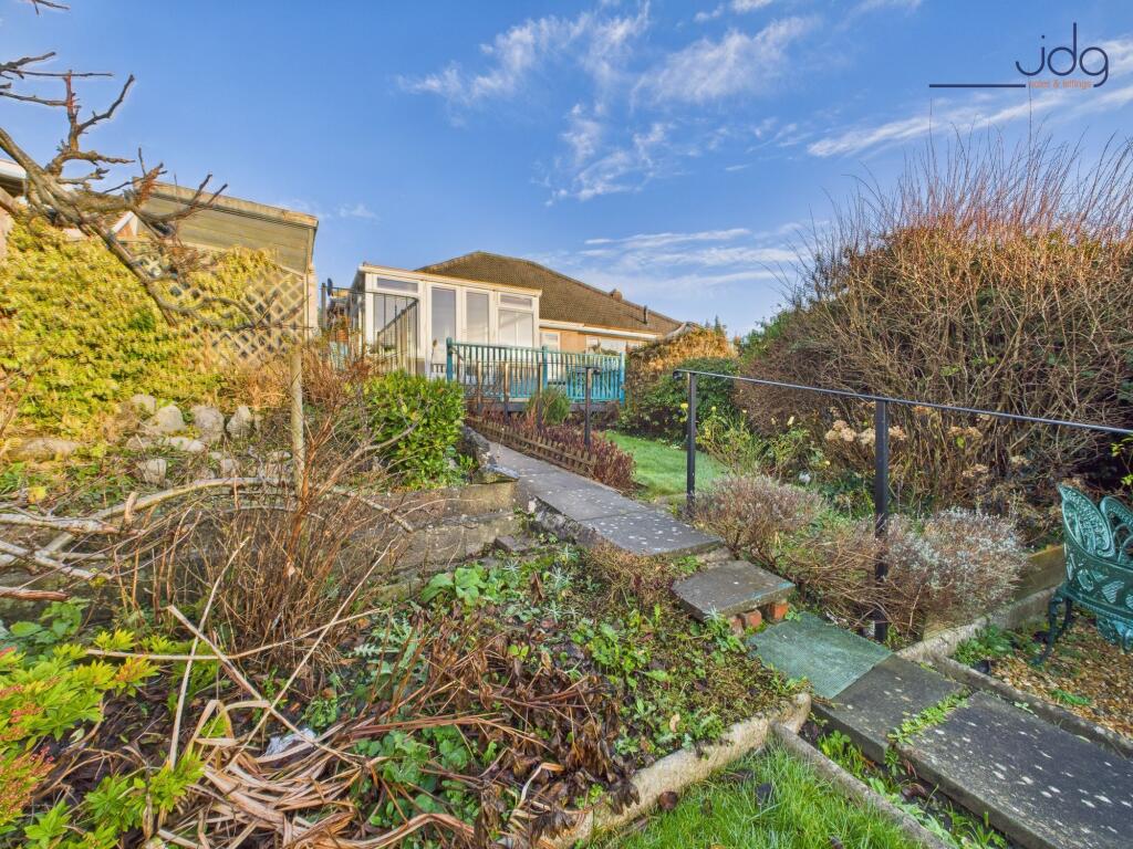 A generous, tiered rear garden with paved seating areas and lawn