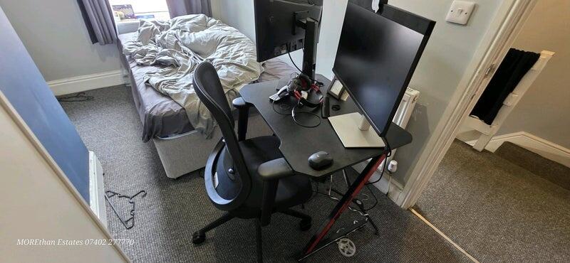 A cozy single bedroom featuring a compact study...