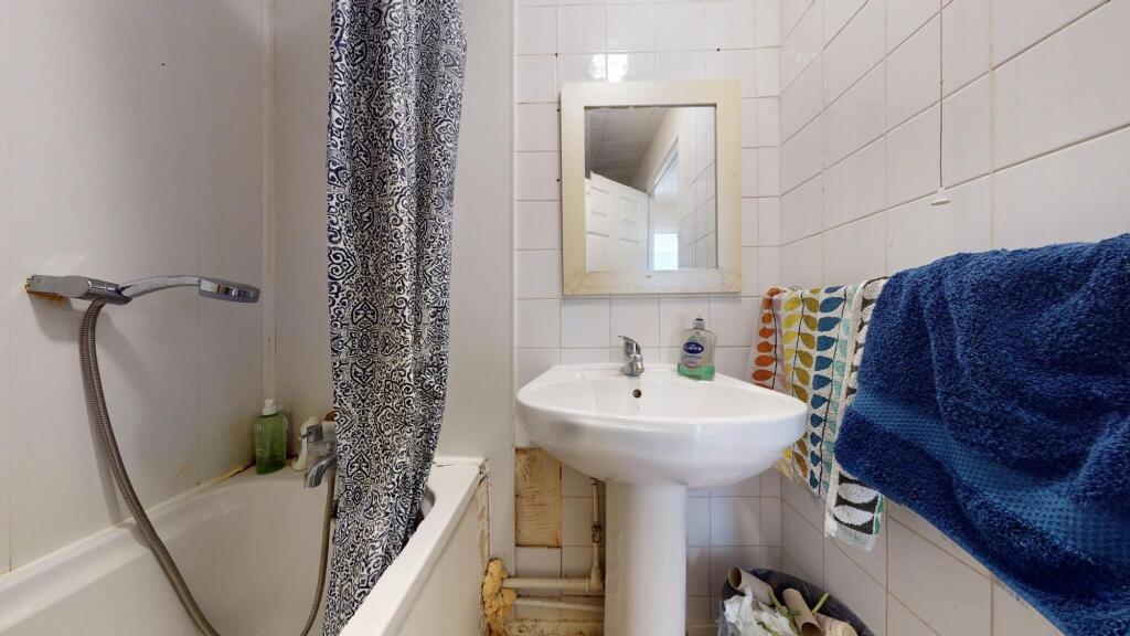 A compact bathroom featuring a white pedestal s...
