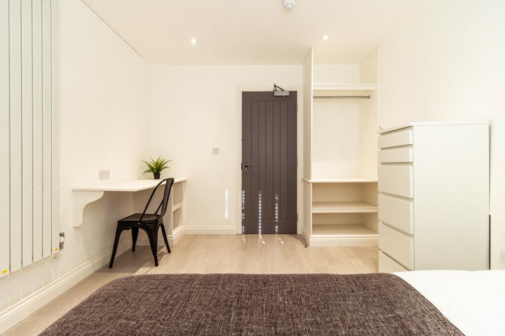 Bright, modern bedroom with built-in shelving a...