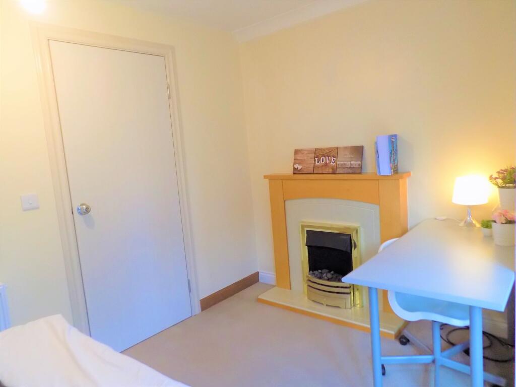 A cozy single bedroom featuring a tidy workspac...