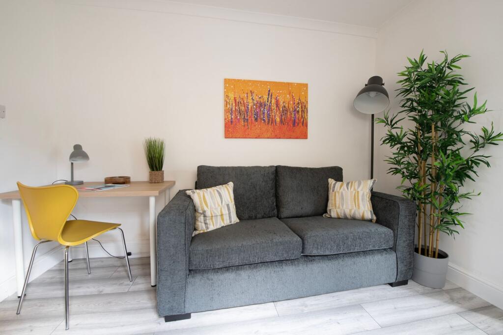 A bright, modern living room featuring a comfor...