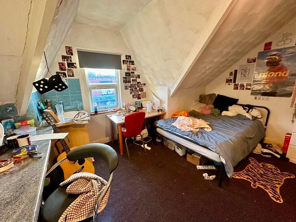 A cozy single bedroom featuring a sloped ceilin...