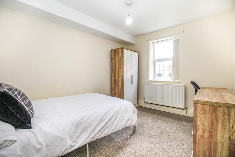 A bright single bedroom featuring a comfortable...