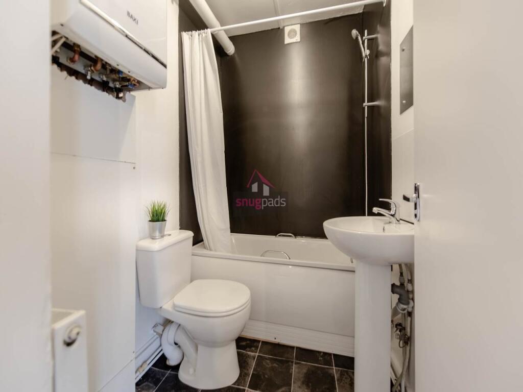 A modern bathroom featuring a white bathtub wit...