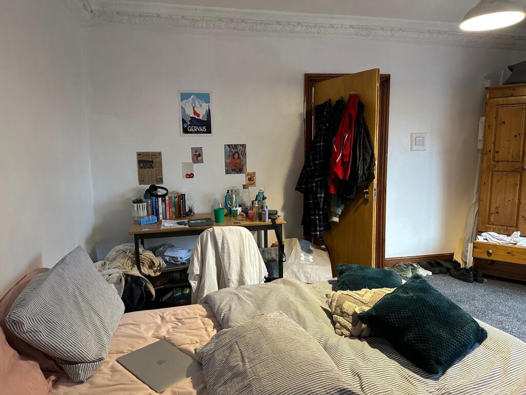 A cozy bedroom featuring a bed, desk, and perso...