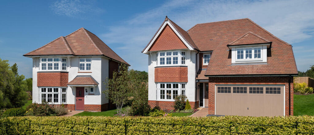 A large detached house with white walls, red brick accents, and a red-tiled roof, surrounded by a gr