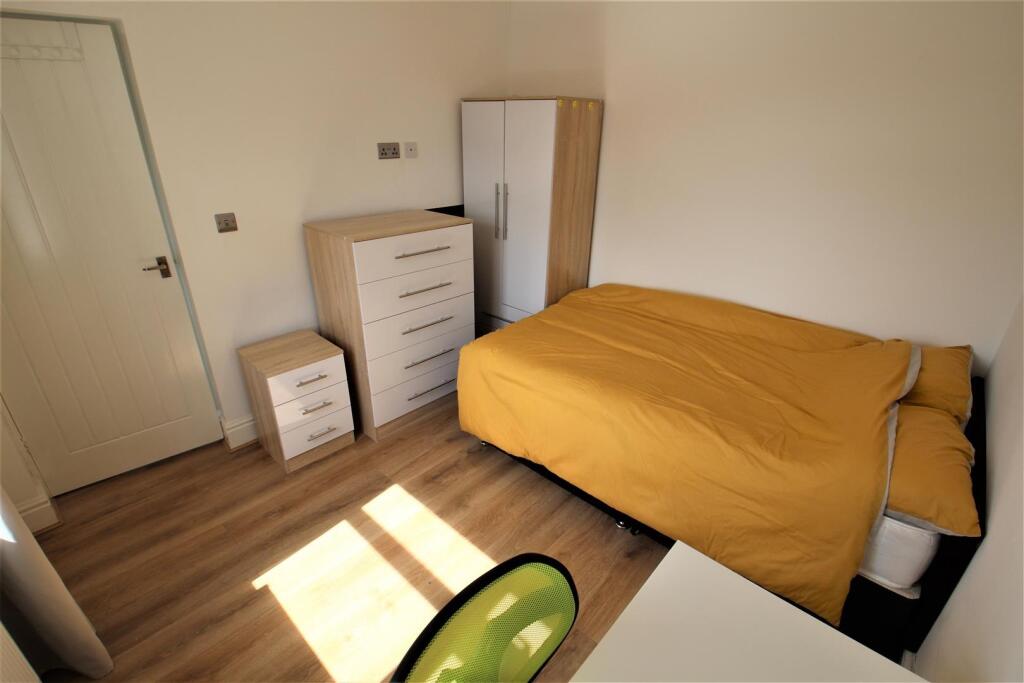 A bright, tidy single bedroom featuring warm wo...