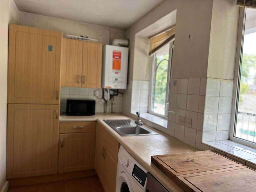Bright kitchen area featuring wooden cabinetry,...