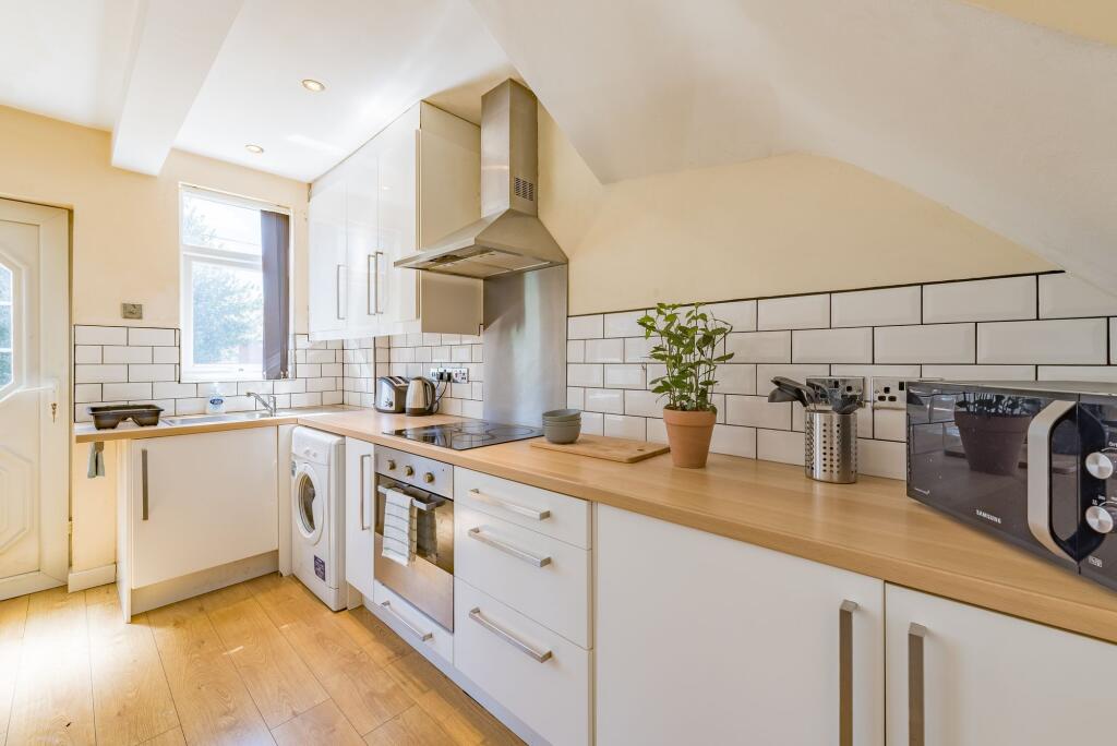 A bright, modern kitchen featuring white cabine...